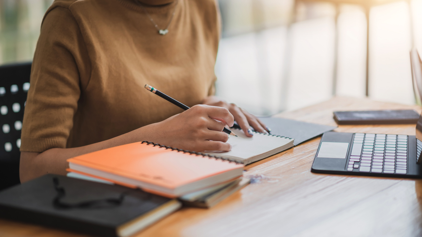 Teacher writing in reflection journal at their desk